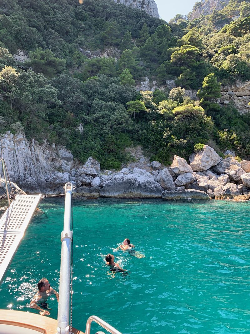 Bagno nell'acqua color smeraldo sotto le falesie di Capri