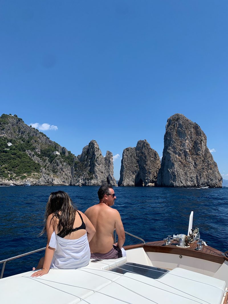 Una coppia seduta a prua guarda i Faraglioni di Capri