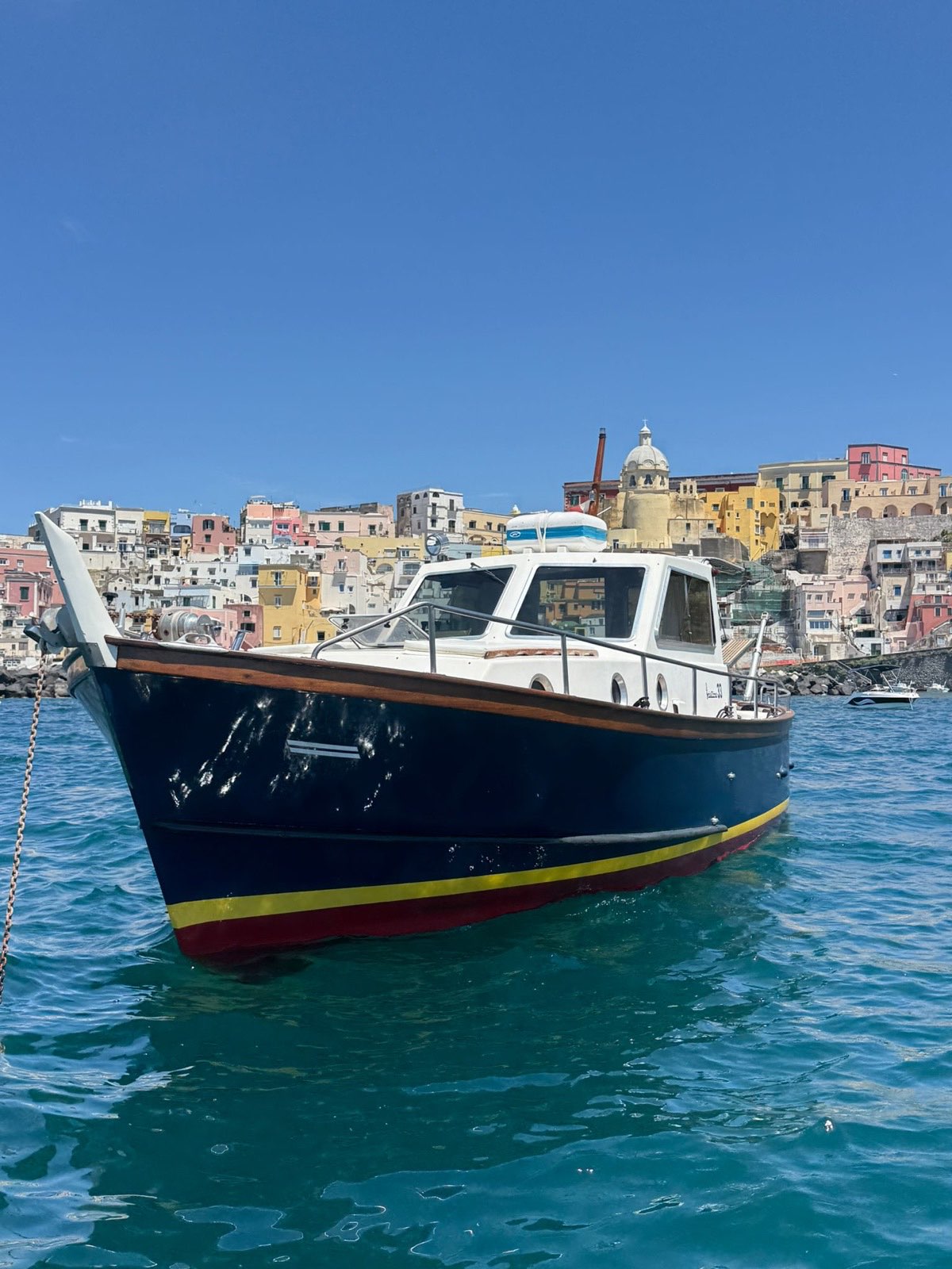 The Sciallino 33 riding at anchor on its chain in front of Procida's pastel houses