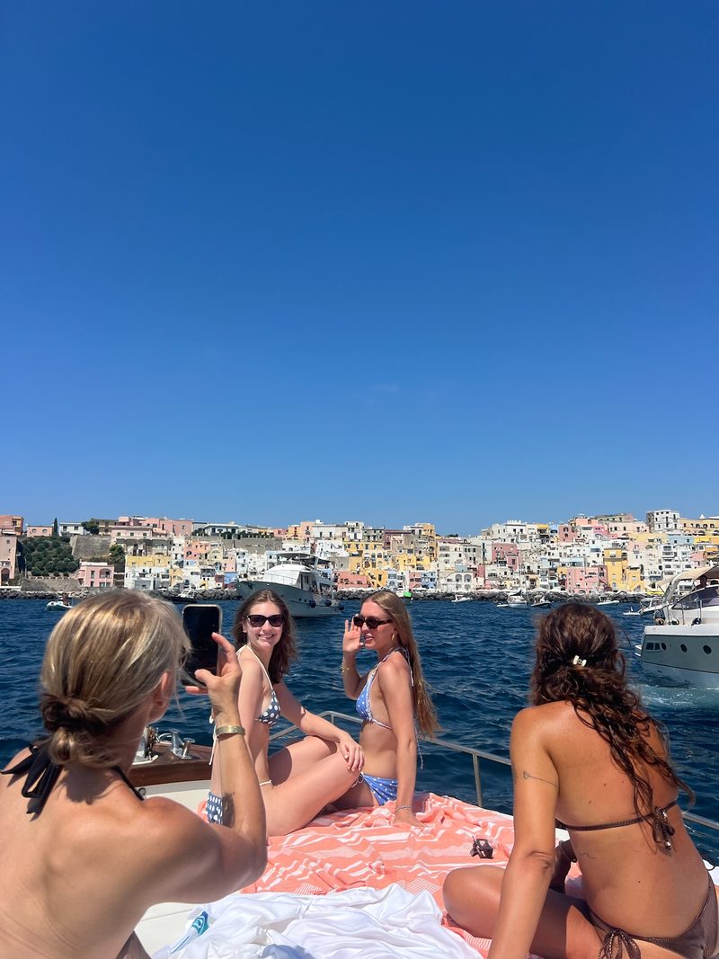 Un gruppo prende il sole a prua davanti a Procida