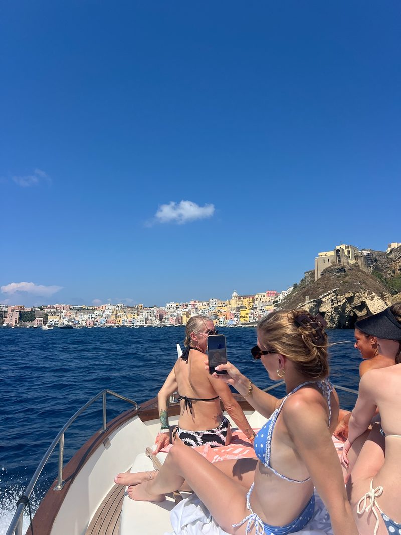 Ospiti a prua davanti alle case colorate di Procida